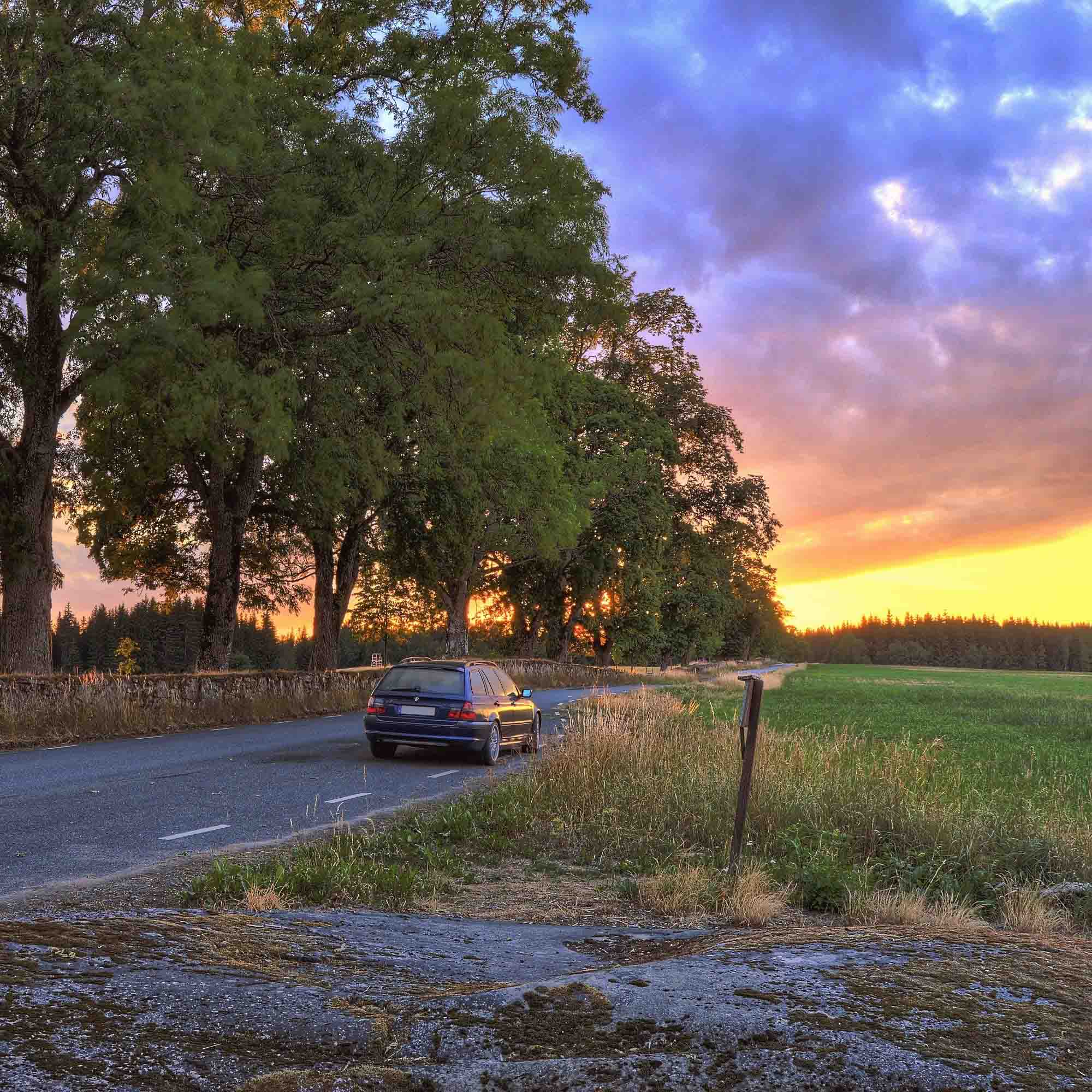 Parkerad bil i landskap med solnedgång
